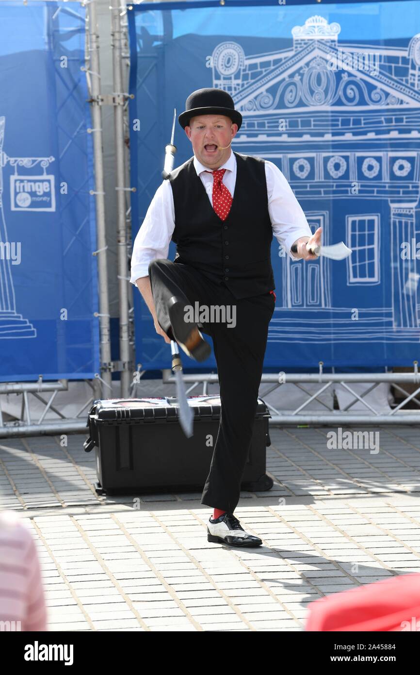 2019. Edinburgh Festival. Street Performer on Princess Street does his knife juggling act to his audience. Stock Photo