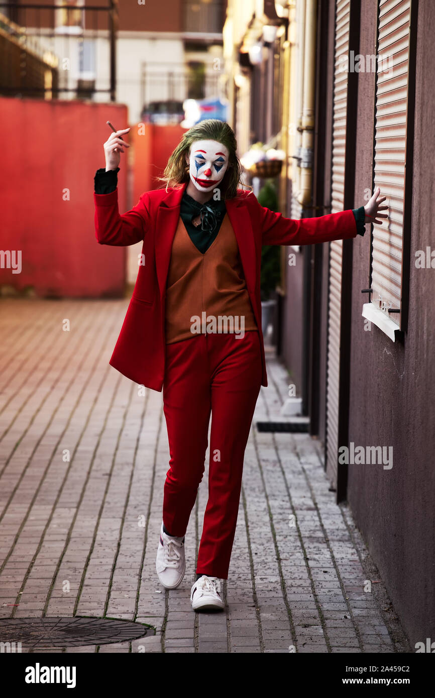 young woman with Joker makeup and costume, walks smoking Stock Photo - Alamy