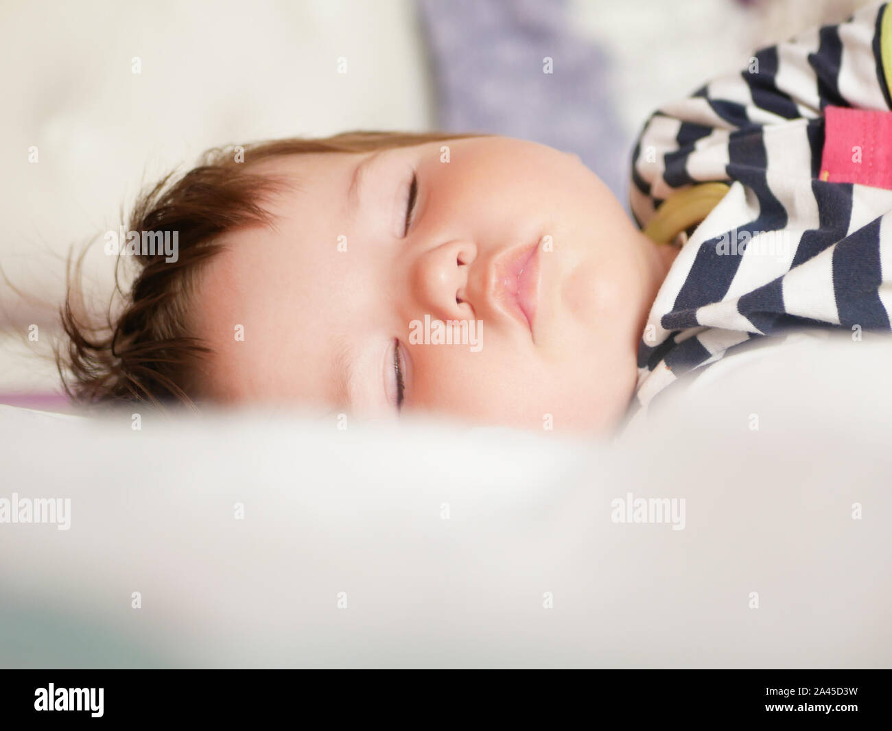 baby sleeps in parents bed. arms outstretched baby's restful sleep. close-up. child 0-1 years old. adorable lovely baby sleeps calmly in bed, has a Stock Photo