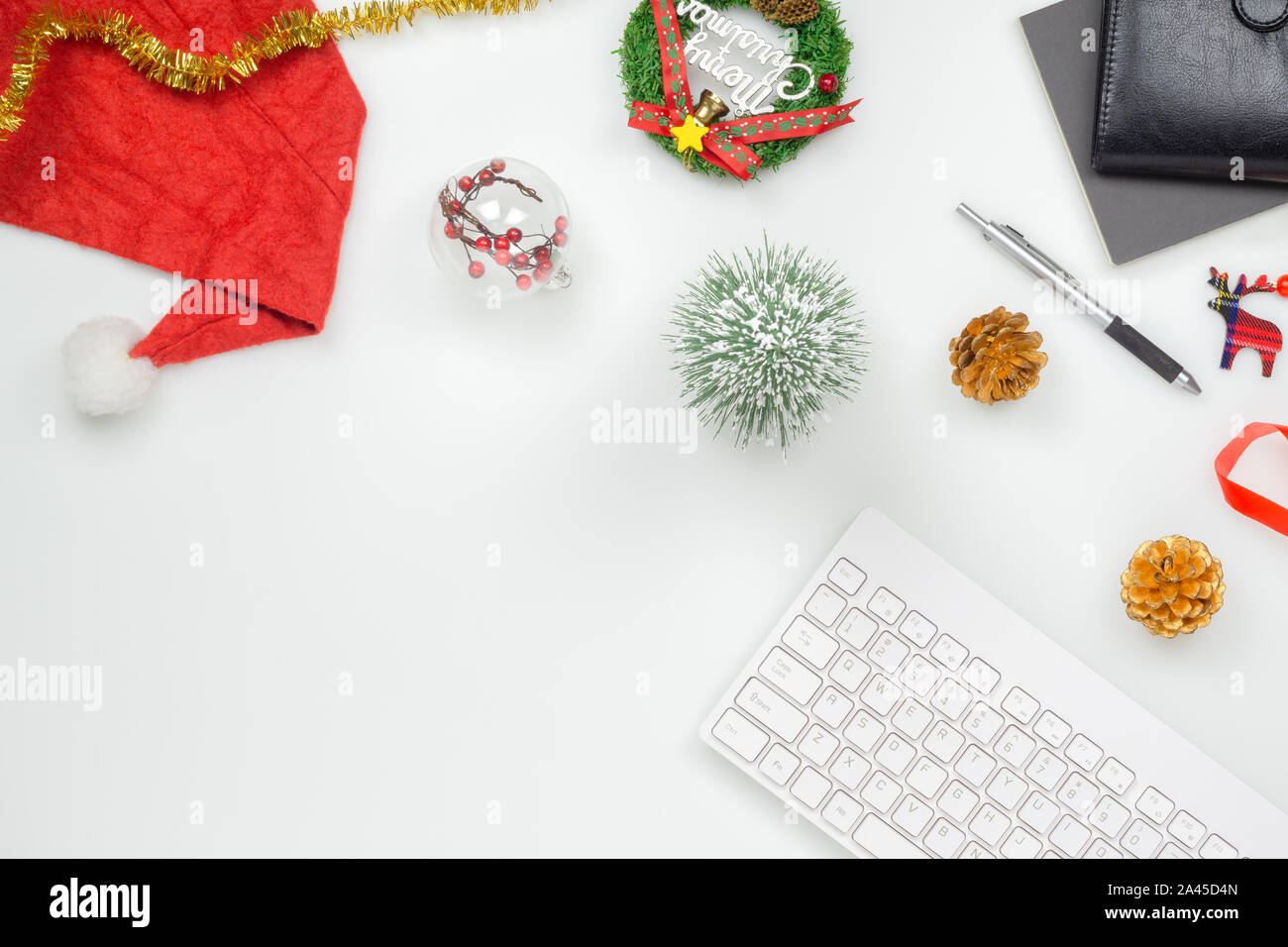 Flat lay top view office table desk, Christmas workspace with keyboard, Santa Claus hat and christmas decorations on white background Stock Photo