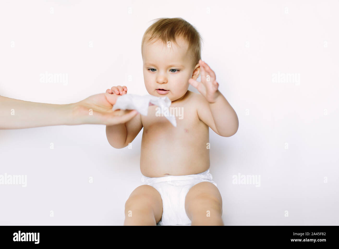 Hygiene young momy wiping the baby skin with wet wipes. Little baby girl in diaper sitting and