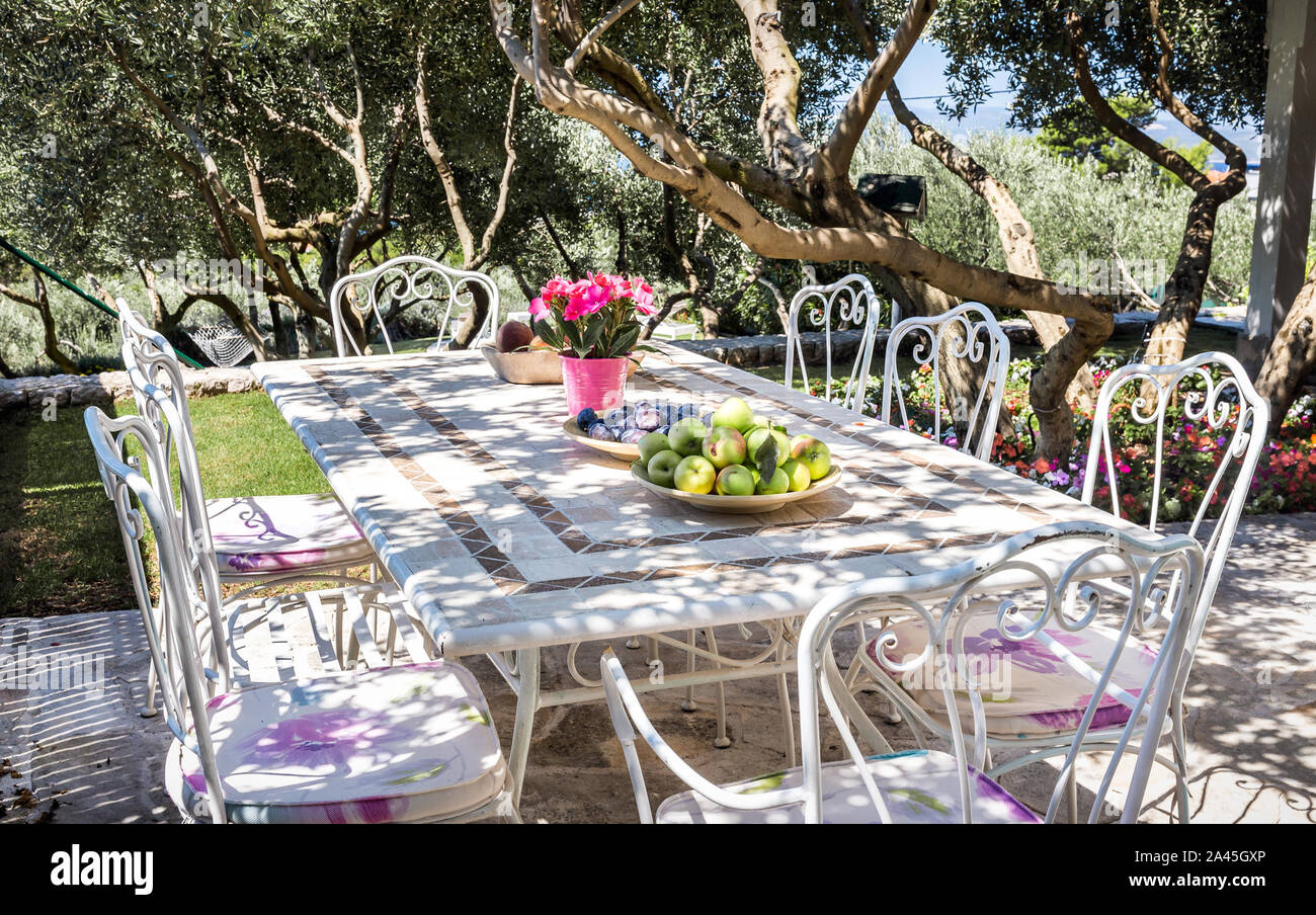 Beautiful garden, table setting prepared for a meal and view on Mediterranean sea Stock Photo