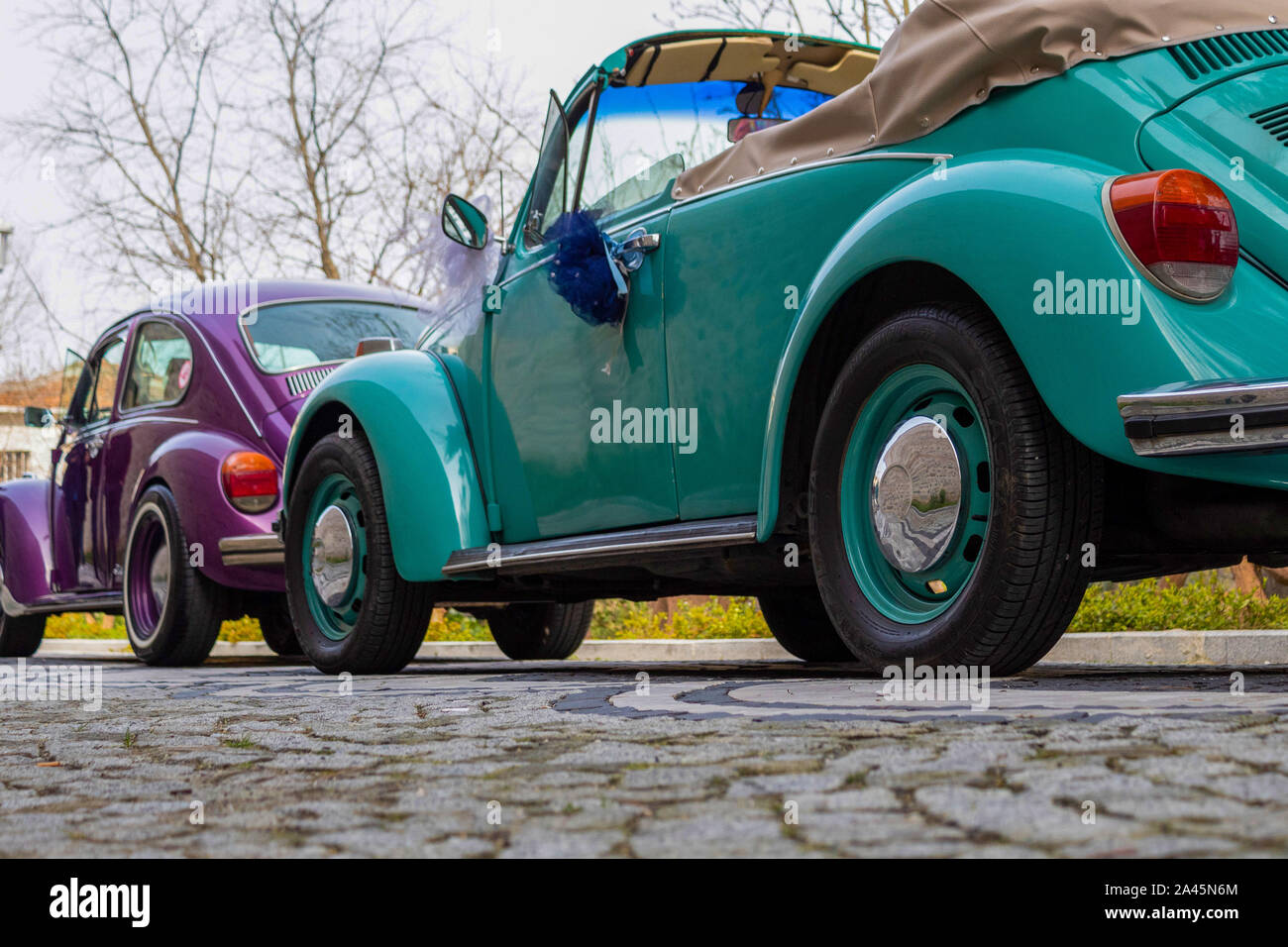 Green and purple colored two classic cars on stone ground