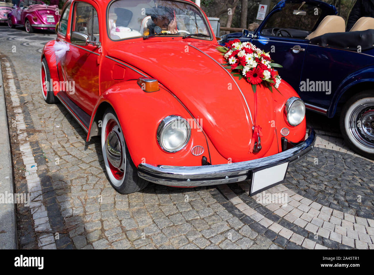 A man driving red flower ornate classic car on stone ground Stock Photo