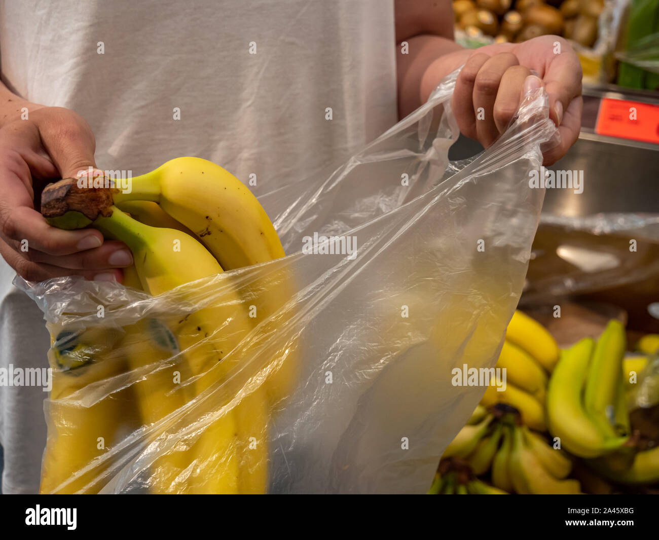 Customer is packing bananas in plastic bag in the supermarket Stock