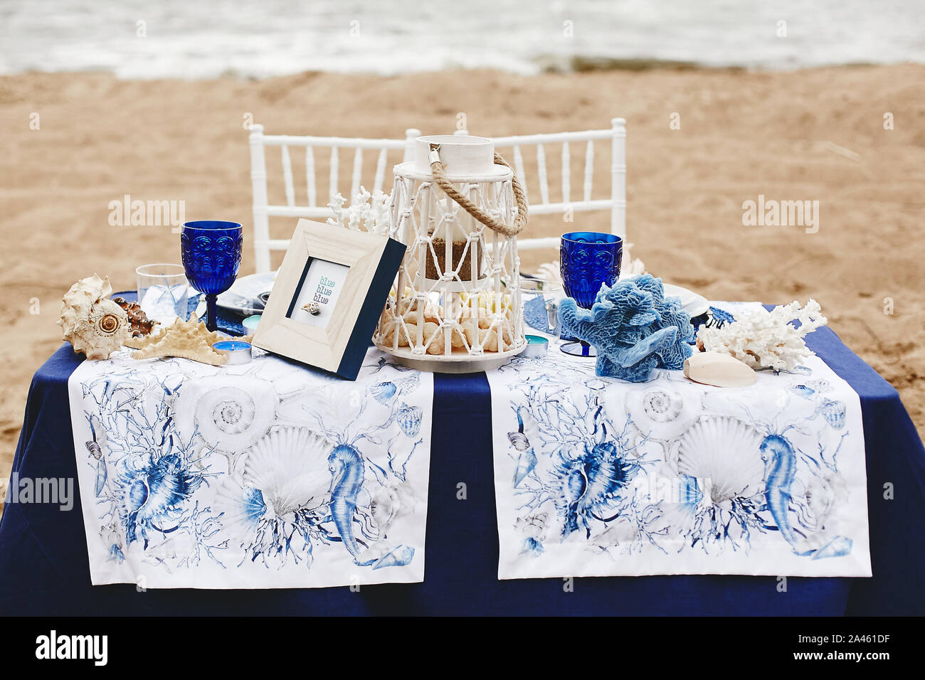 https://c8.alamy.com/comp/2A461DF/wedding-decoration-in-a-marine-style-table-for-the-bride-and-groom-on-a-sandy-beach-decorated-with-sea-shells-corals-candlelight-and-wineglass-2A461DF.jpg