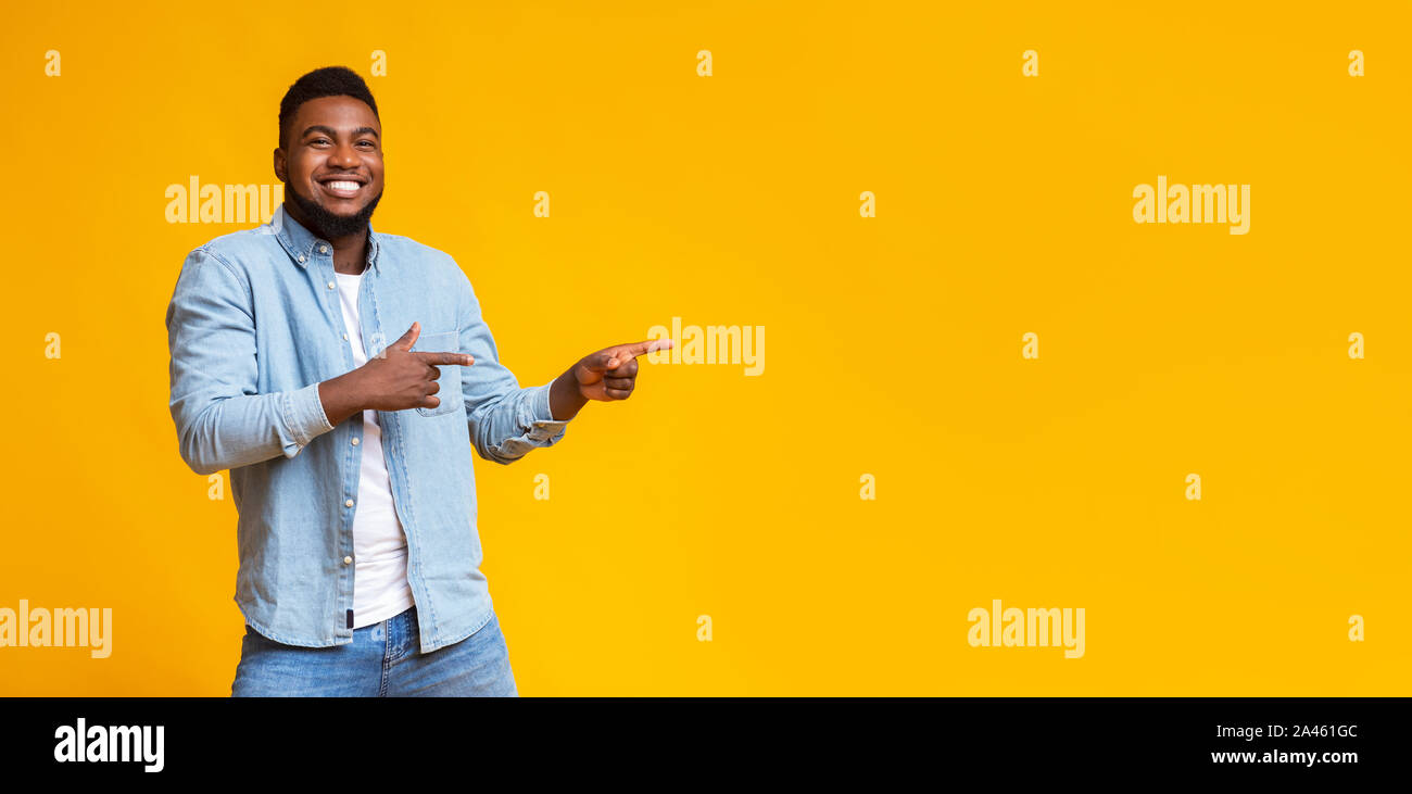 Cheerful black guy pointing two fingers aside at copy space Stock Photo