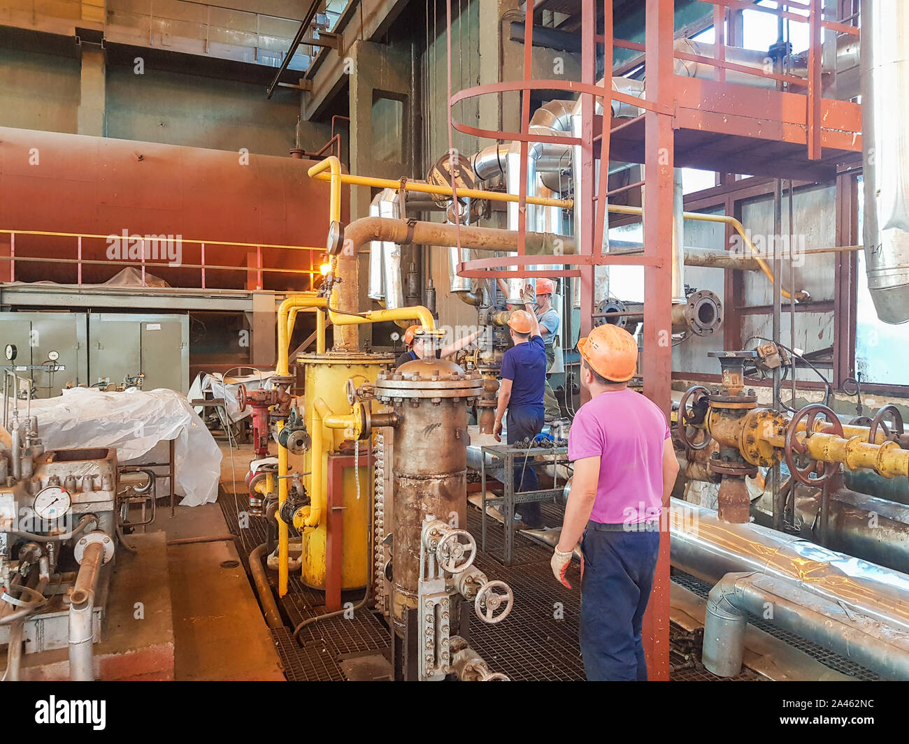 Workers at the factory. chemical plant indoors. pipe repair. factory worker by car. heating shop. Stock Photo