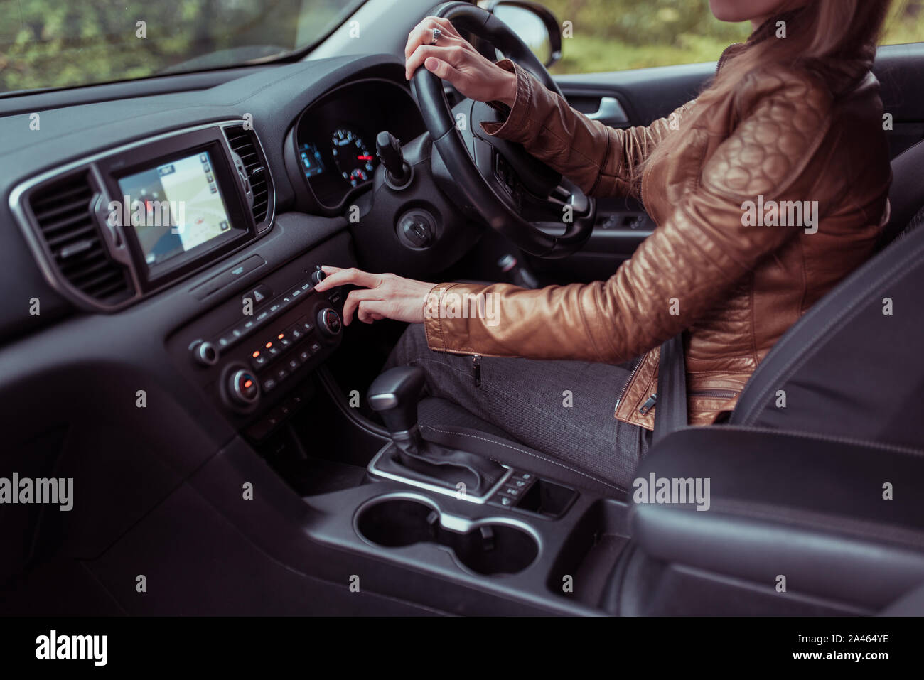 woman driving car, summer autumn forest, turns volume on off radio