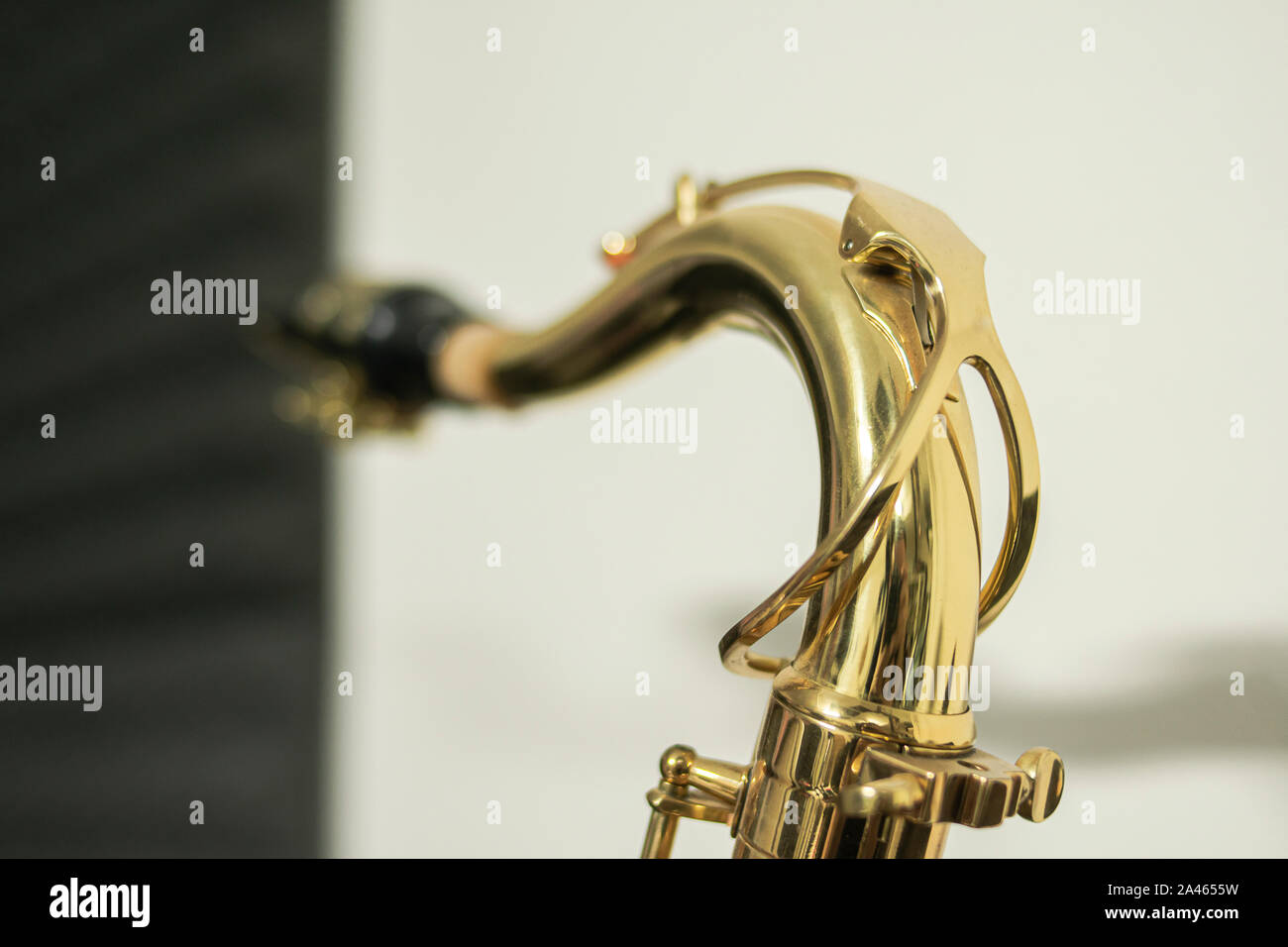 Close-up of the tudel or neck of a golden and shiny tenor sax where you can see the construction details of it Stock Photo