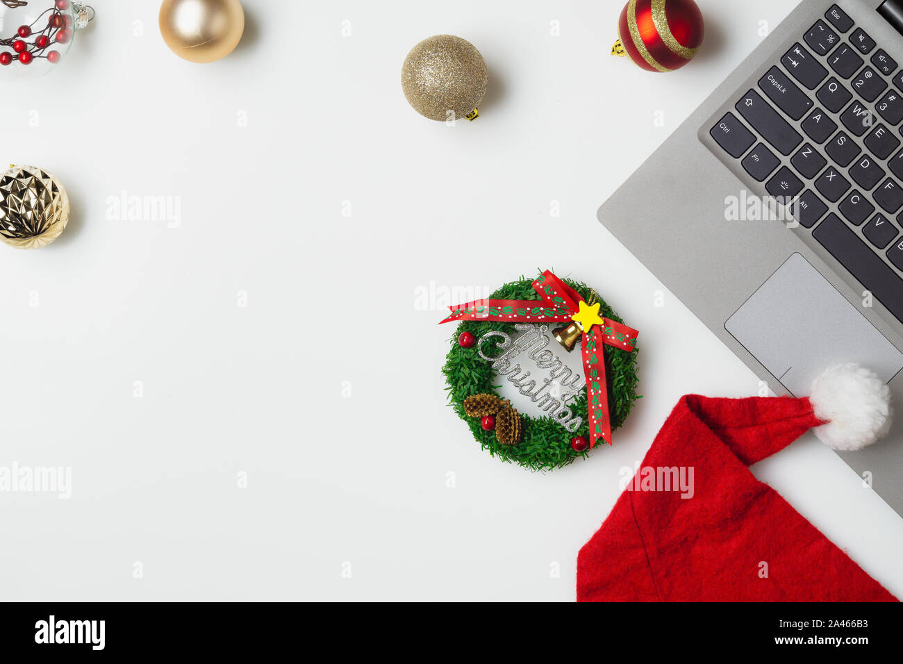 Flat lay top view Christmas office table desk party concept, Christmas workspace with laptop, Santa Claus hat and Christmas decorations on white backg Stock Photo