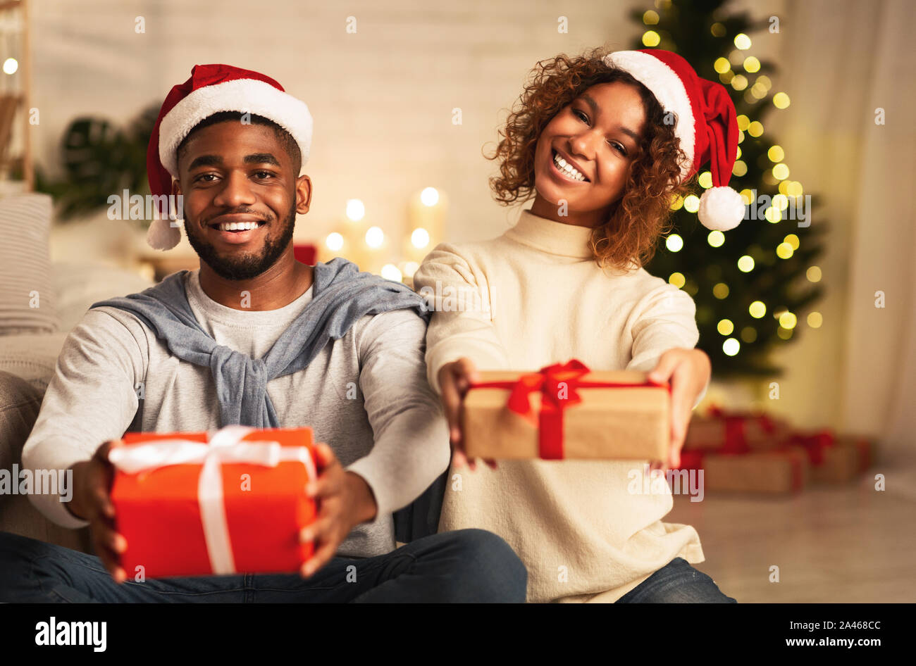 Happy New Year! Afro couple stretching gift boxes Stock Photo