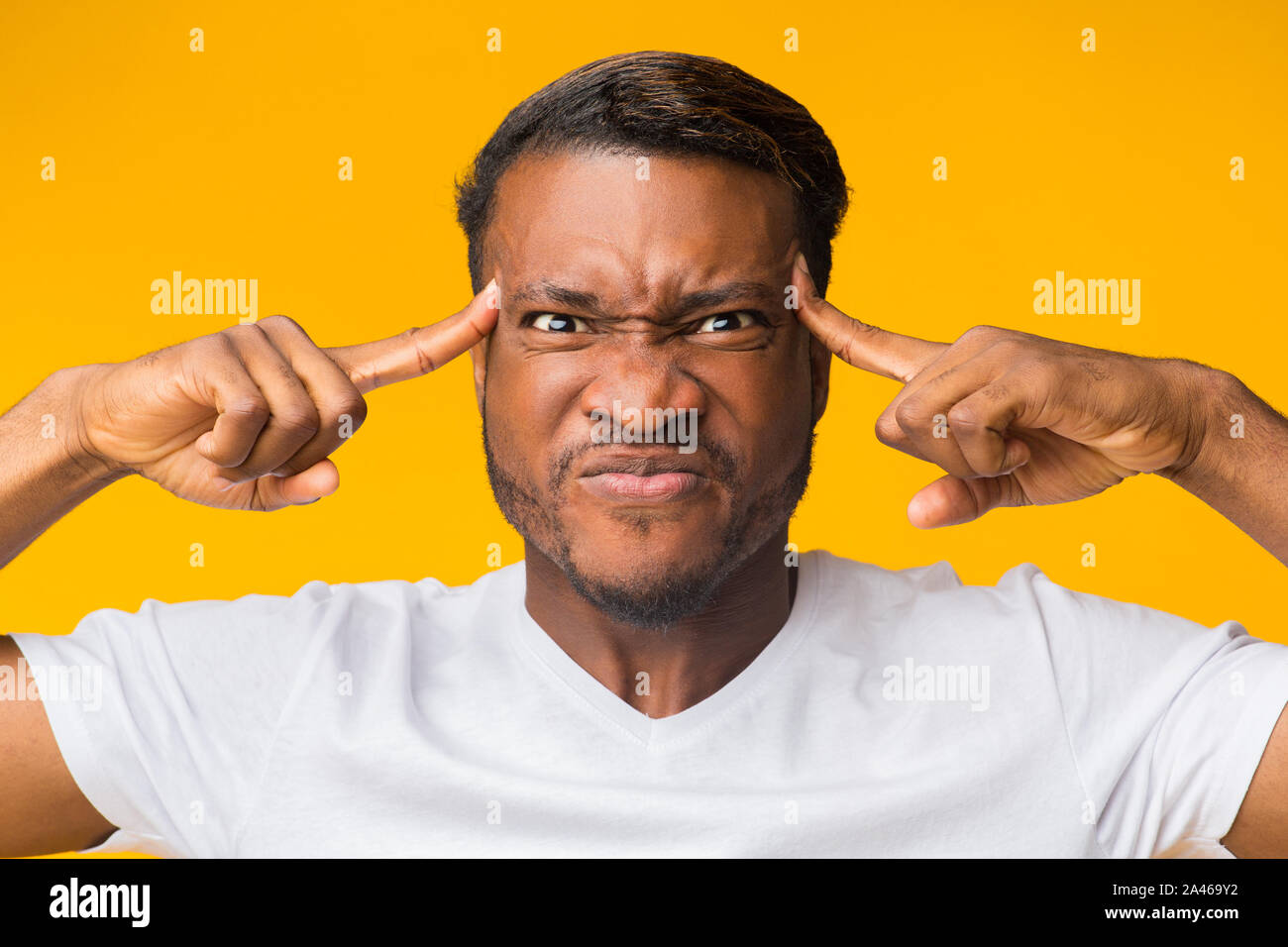 Black Man Concentrating Hard Pointing Fingers At Forehead In Studio Stock Photo