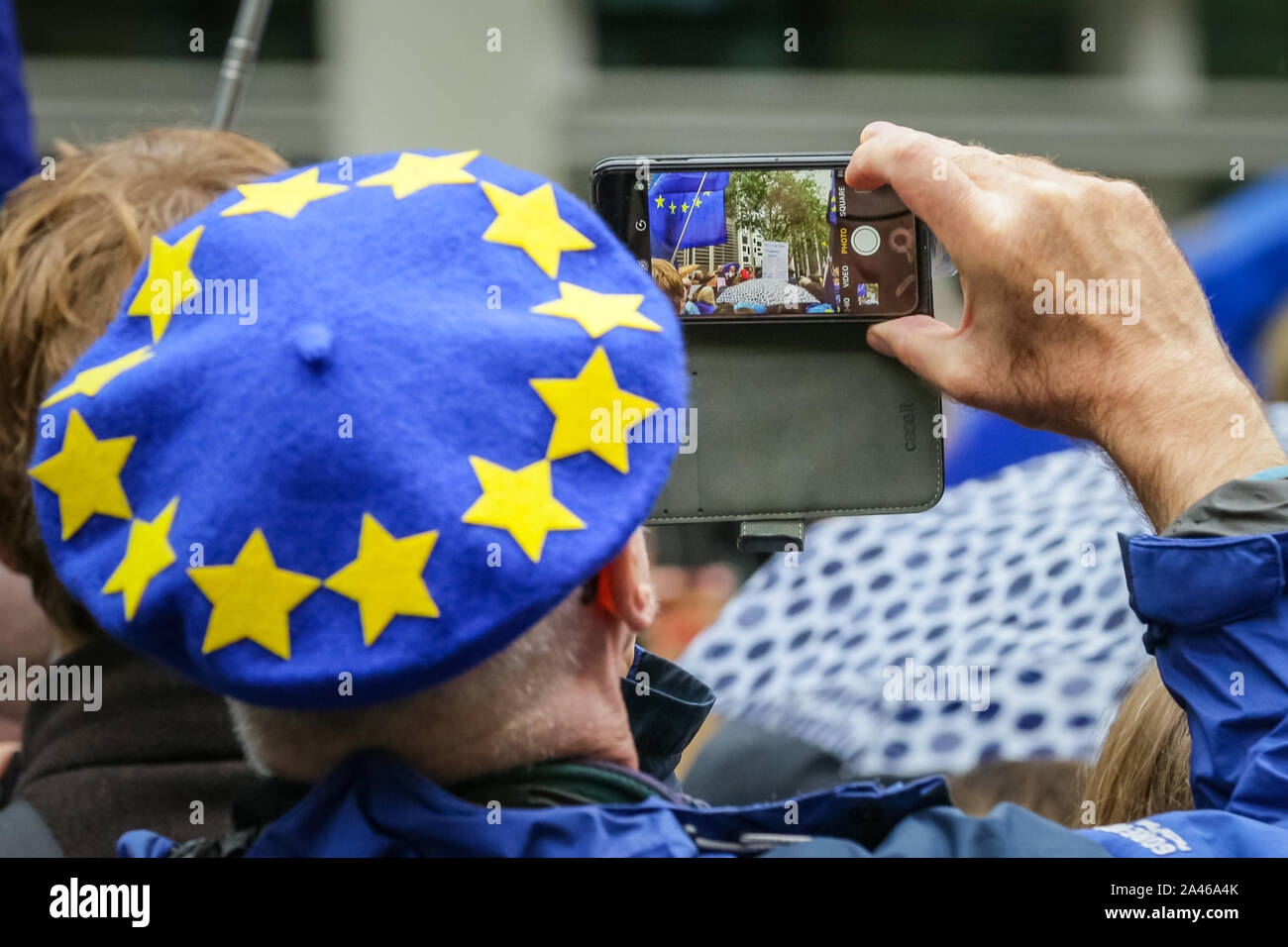 London, UK, 12 Oct 2019. A protester with blue and yellor beret takes pictures of the rally. Protesters rally in Westminster to defend the rights of the 5 million+ European Citizens living in the UK and British Citizens in the EU who are directly affected by Brexit. Key speaker and rally sites include outside Europe House, the European Parliament UK offices, The Home Office and 55 Tufton Street, base of several Eurosceptic and Brexit-related think tanks. Stock Photo