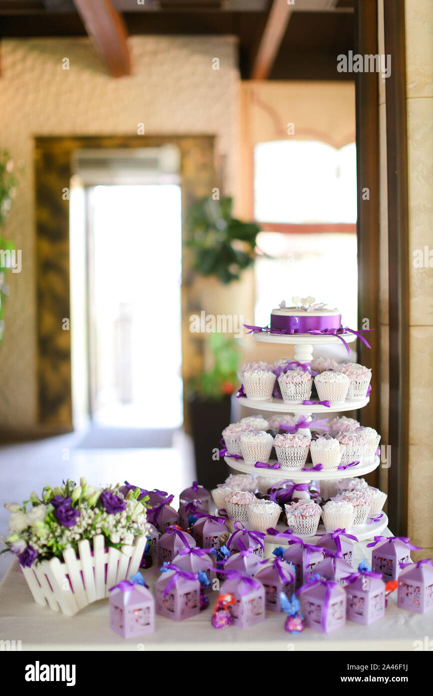 Violet decorations and sweet delicious cakes for party. Concept of birthday sweets and tasty food. Stock Photo
