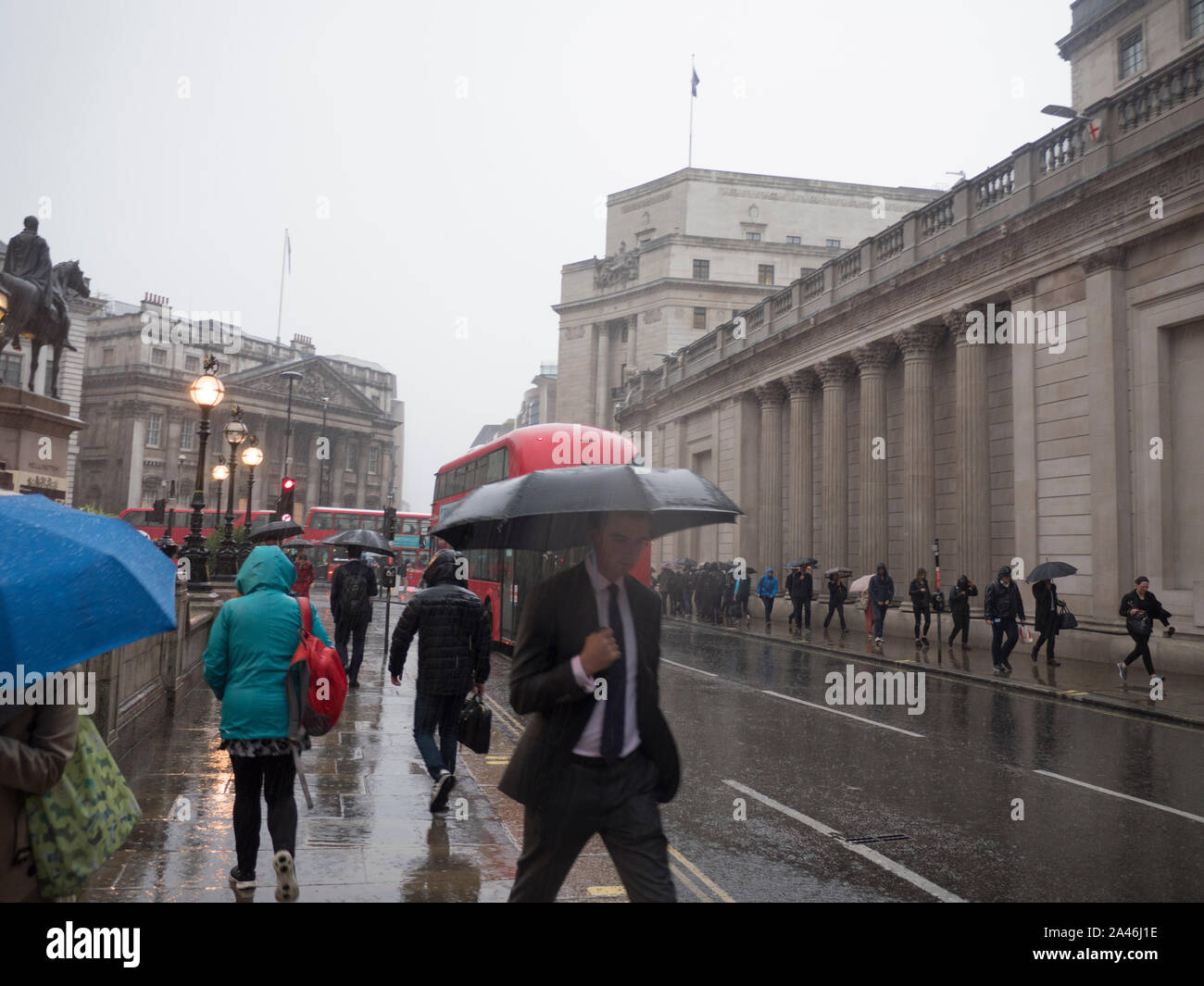 Pouring rain outside the bank of england with commuters and city