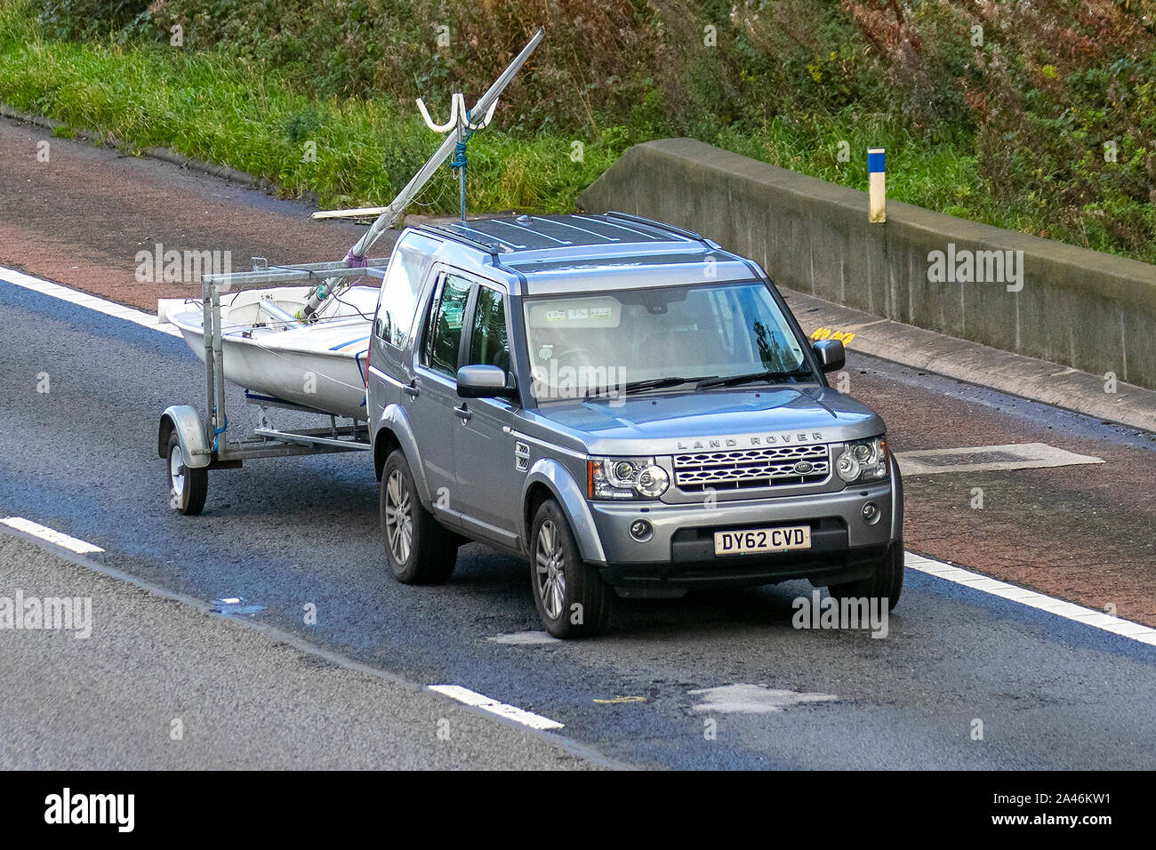 2012 GREY SILVER Land Rover Discovery XS Sdv6 Auto towing yacht on trailer; UK Vehicular traffic, transport, modern, saloon cars, south-bound on the 3 lane M6 motorway highway. Stock Photo