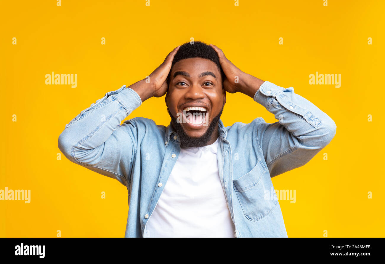 Amazed man holding hands on head and looking at camera Stock Photo