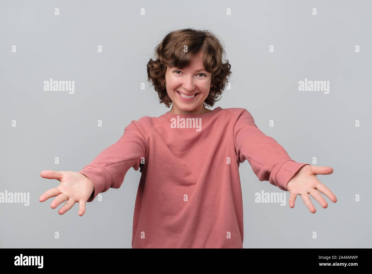 Girl in red sweater with stretched hands wants to hug her firends Stock Photo