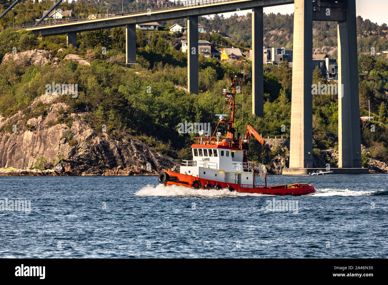 Small tug boat Lars passing under Askoy (Askøy) suspension bridge, outside port of Bergen, Norway Stock Photo