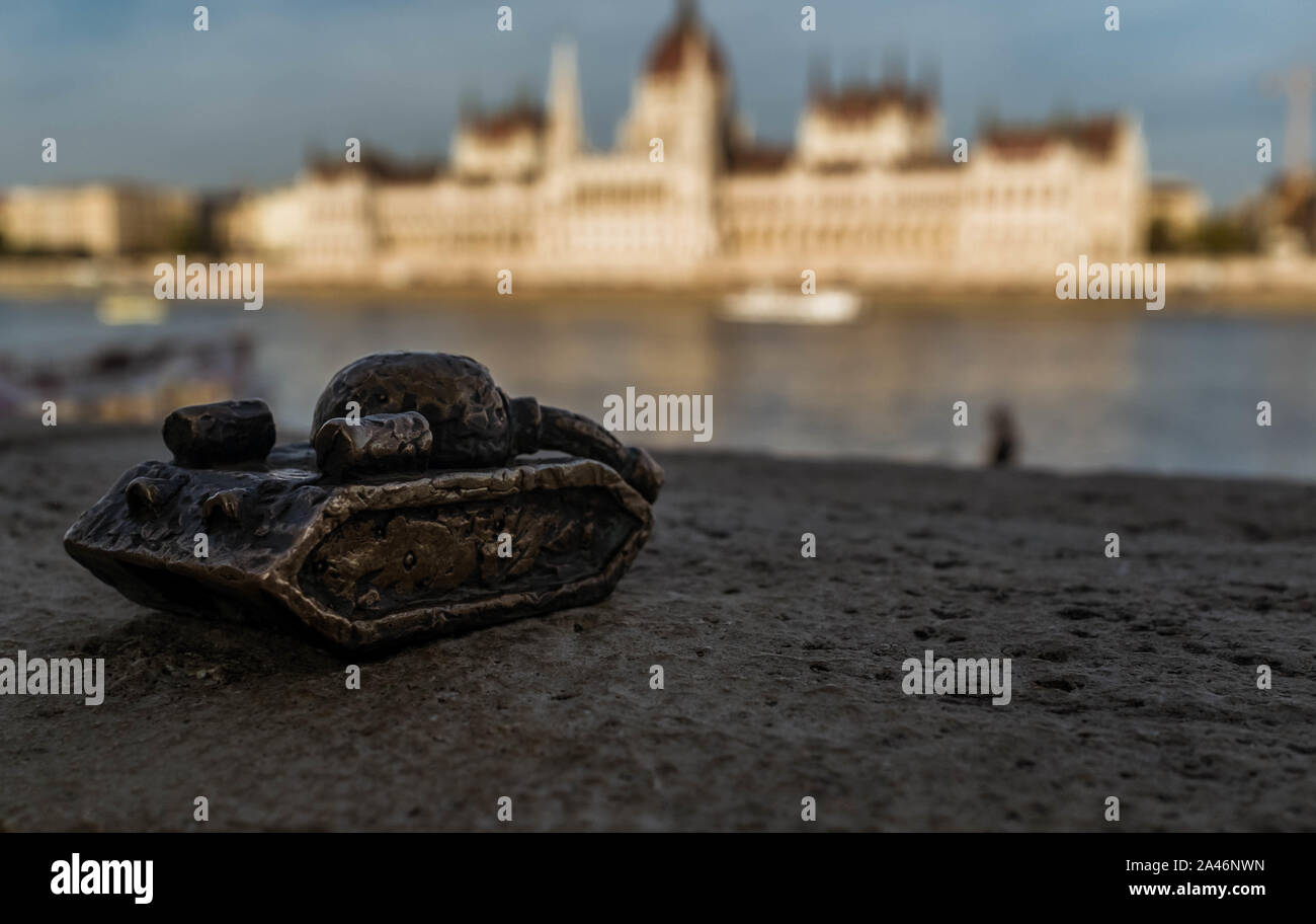 Mini bronze tank figurine by Mykhailo Kolodko with Hungarian Parliament building on a bokeh background. Stock Photo