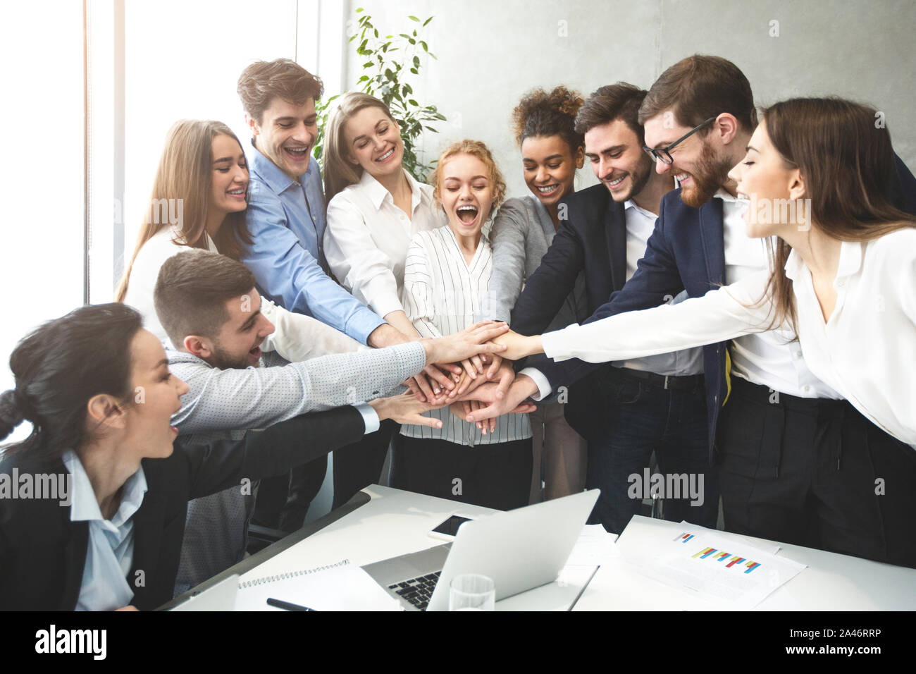 Happy business team joining hands together, celebrating success Stock Photo