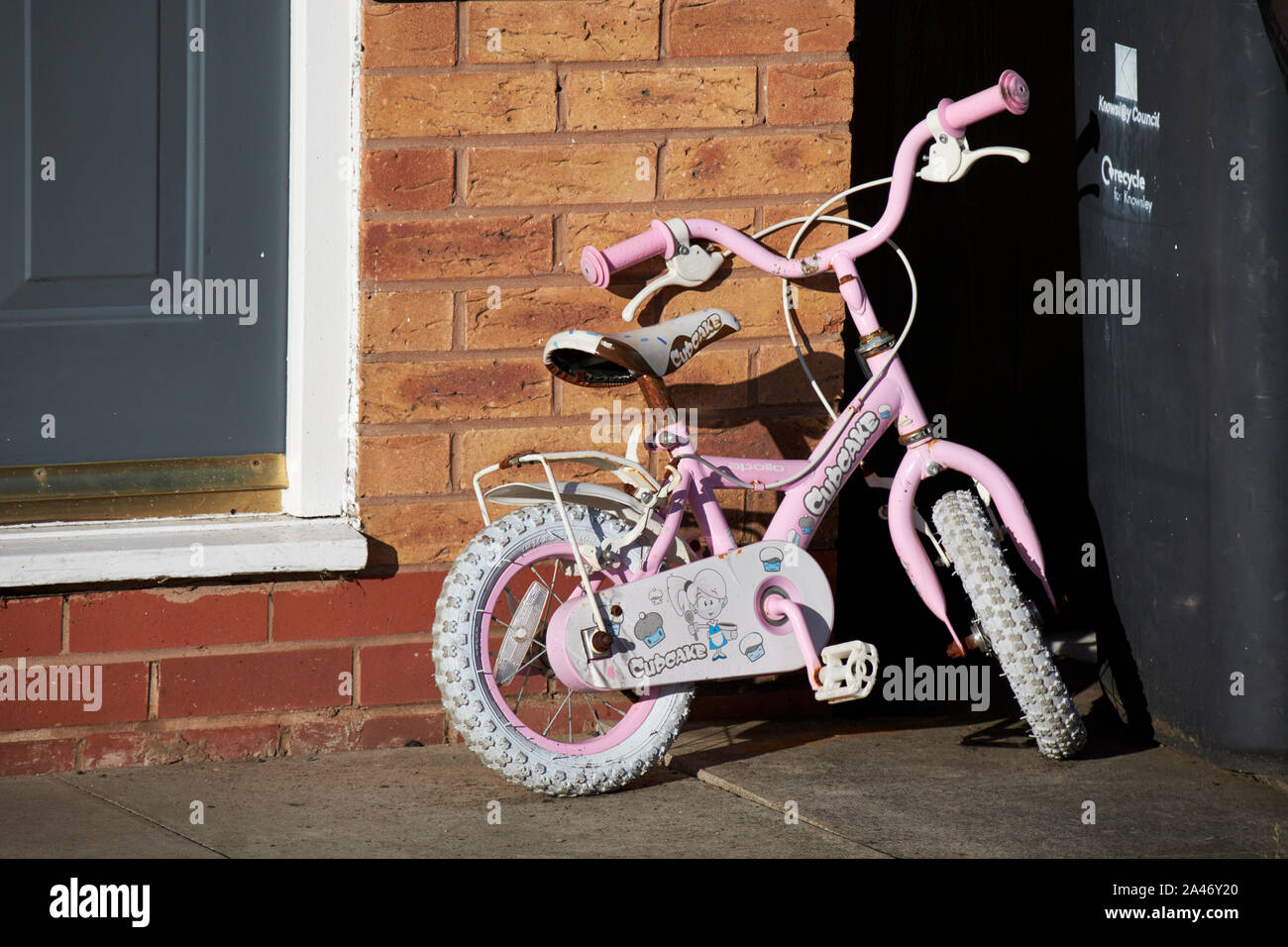 old used little girls bicycle left on doorstep of a house England UK Stock Photo