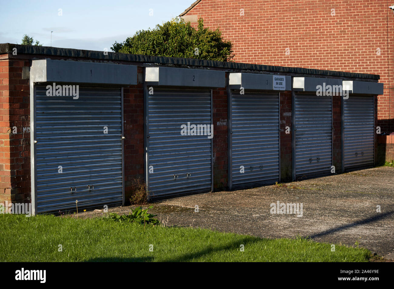 steel roll up shutters on closed local lock up garages on a residential street Liverpool England UK Stock Photo