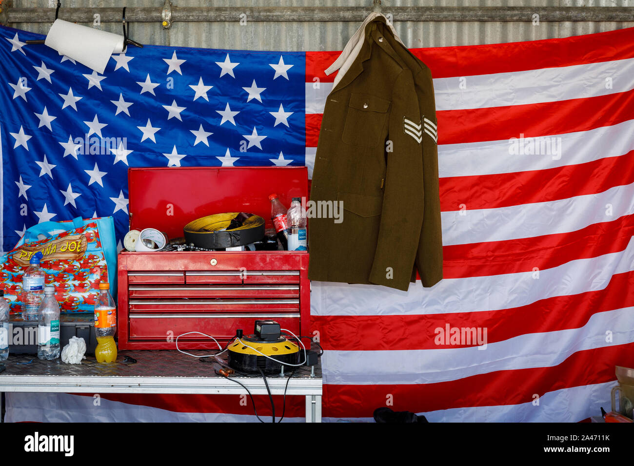 American flag hanging with military jacket and toolbox in the motorcycle paddock garage at the 2019 Goodwood Revival, Sussex, UK. Stock Photo