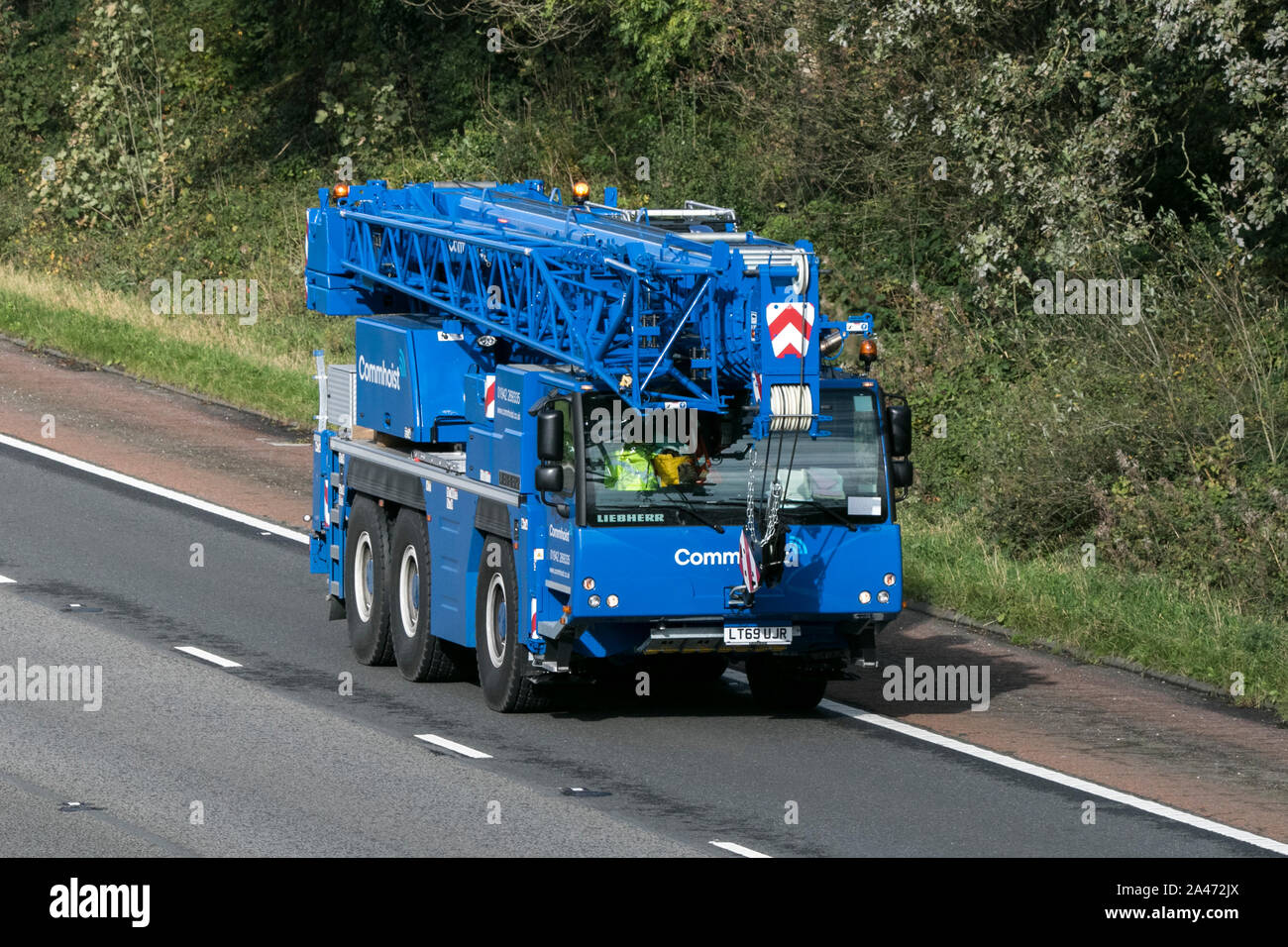 Commhoist telecoms Liebherr blue mobile crane traveling on the M61 motorway near Manchester, UK Liebherr-Werk Ehingen GmbH Stock Photo