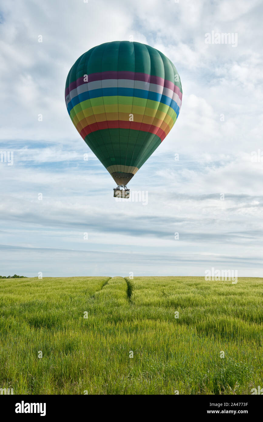 Hot air balloon flying low over farm fields. Midlothian, Scotland Stock Photo