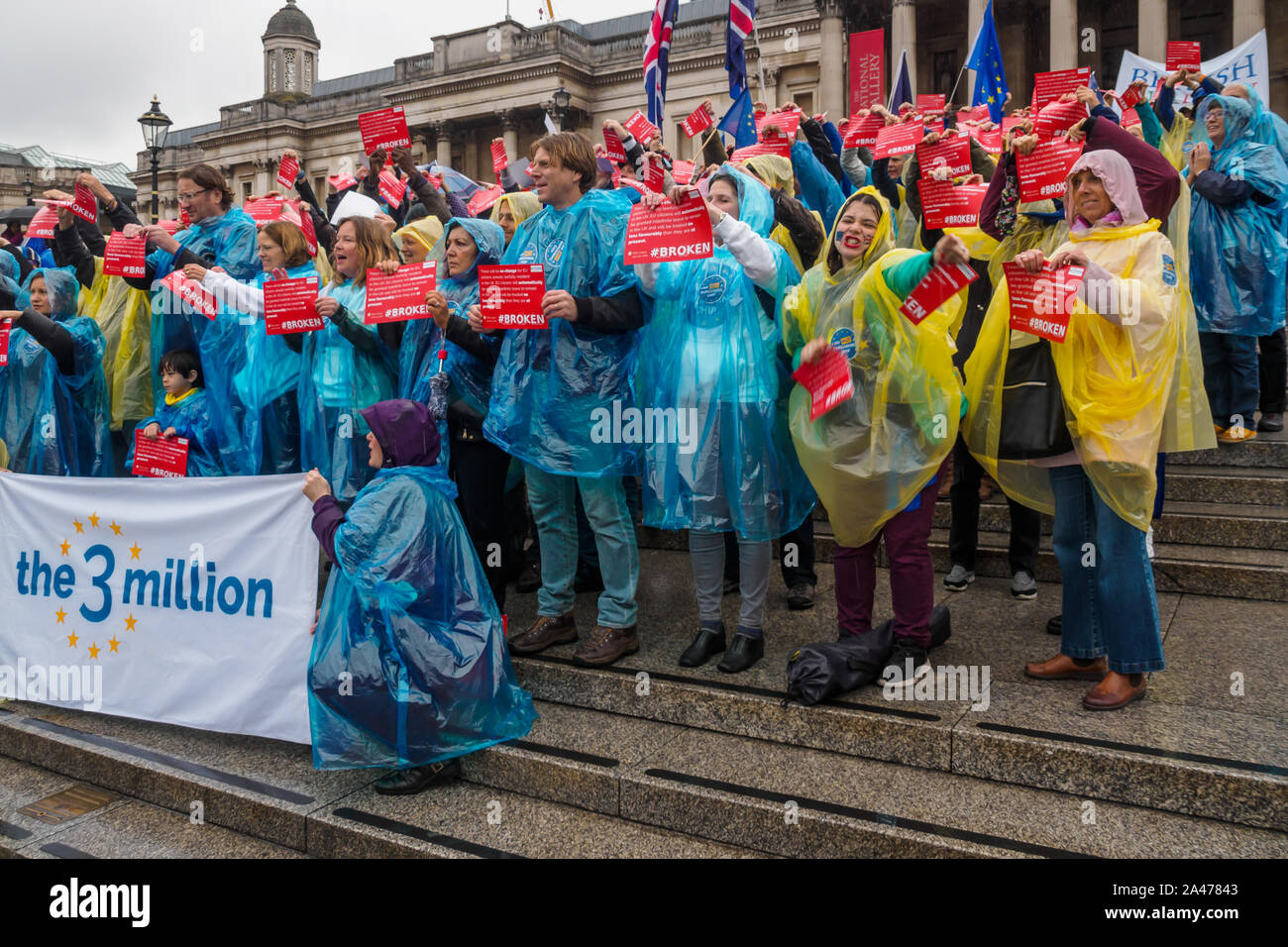 London, UK. 12th October 2019. People  tear up copies of Vote Leave's broken pledge to EU citizens living here. Some of the 3 million EU citizens residents in the UK at an event organised by the3million organisation to express their love for the UK and to remind the Prime Minister ofe his broken promise to us on 1 June 2016. They wore ponchos in the blue and yellow of the European flag. The government settlement scheme is full of flaws and many who have applied have not been granted settled status, and government minister Brandon Lewis has stated that those who have failed to achieve it risk d Stock Photo