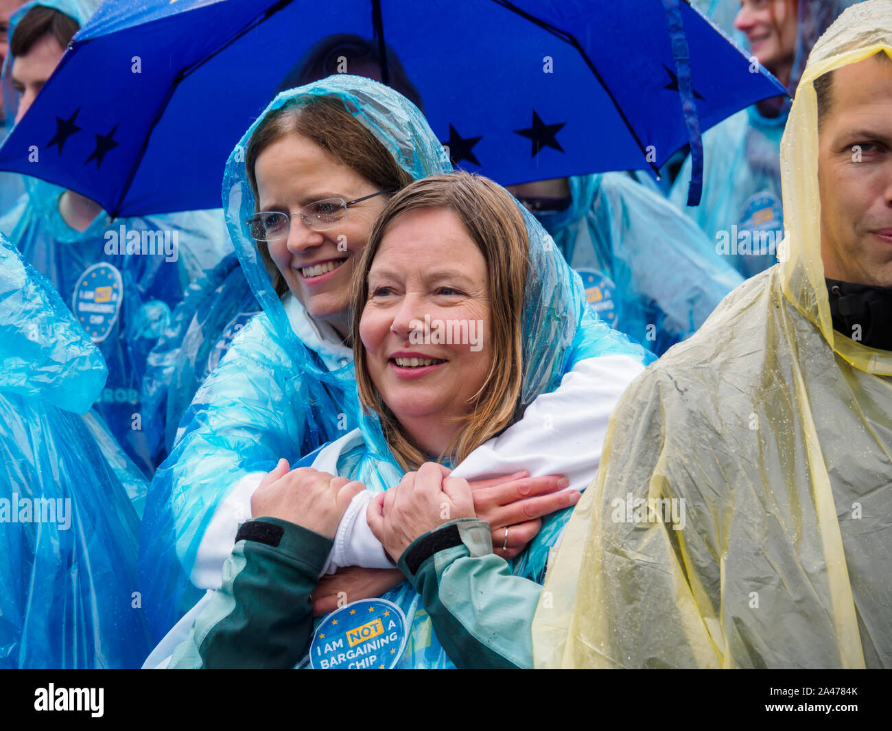 London, UK. 12th October 2019. Some of the 3 million EU citizens residents in the UK at an event organised by the3million organisation to express their love for the UK and to remind the Prime Minister ofe his broken promise to us on 1 June 2016. They wore ponchos in the blue and yellow of the European flag. The government settlement scheme is full of flaws and many who have applied have not been granted settled status, and government minister Brandon Lewis has stated that those who have failed to achieve it risk deportation. They held up copies of Vote Leave's broken promise and tore it up. Pe Stock Photo