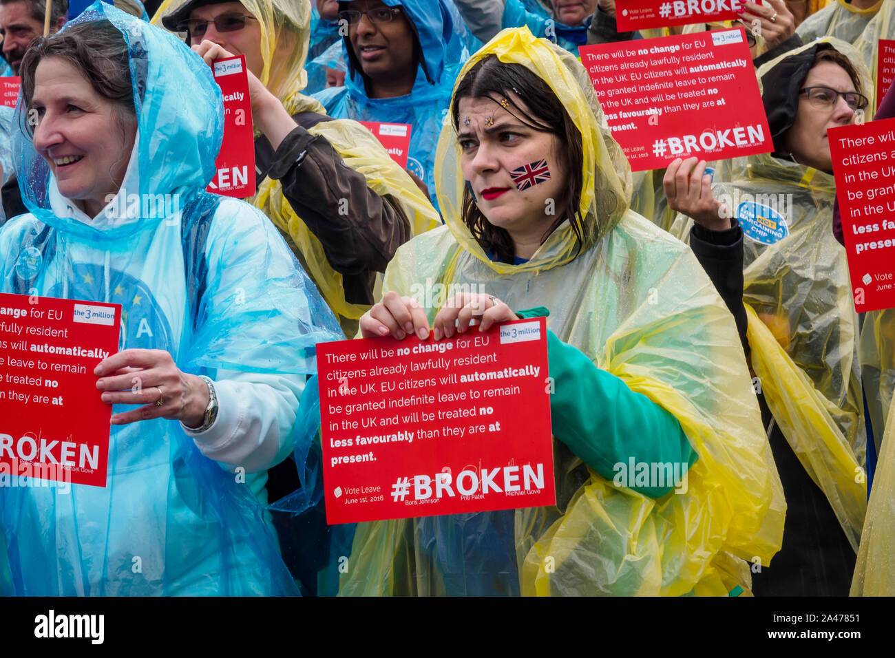 London, UK. 12th October 2019. People prepare to tear up copies of Vote Leave's broken pledge to EU citizens living here. Some of the 3 million EU citizens residents in the UK at an event organised by the3million organisation to express their love for the UK and to remind the Prime Minister ofe his broken promise to us on 1 June 2016. They wore ponchos in the blue and yellow of the European flag. The government settlement scheme is full of flaws and many who have applied have not been granted settled status, and government minister Brandon Lewis has stated that those who have failed to achieve Stock Photo