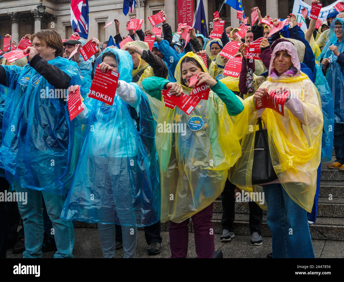 London, UK. 12th October 2019. People  tear up copies of Vote Leave's broken pledge to EU citizens living here. Some of the 3 million EU citizens residents in the UK at an event organised by the3million organisation to express their love for the UK and to remind the Prime Minister ofe his broken promise to us on 1 June 2016. They wore ponchos in the blue and yellow of the European flag. The government settlement scheme is full of flaws and many who have applied have not been granted settled status, and government minister Brandon Lewis has stated that those who have failed to achieve it risk d Stock Photo