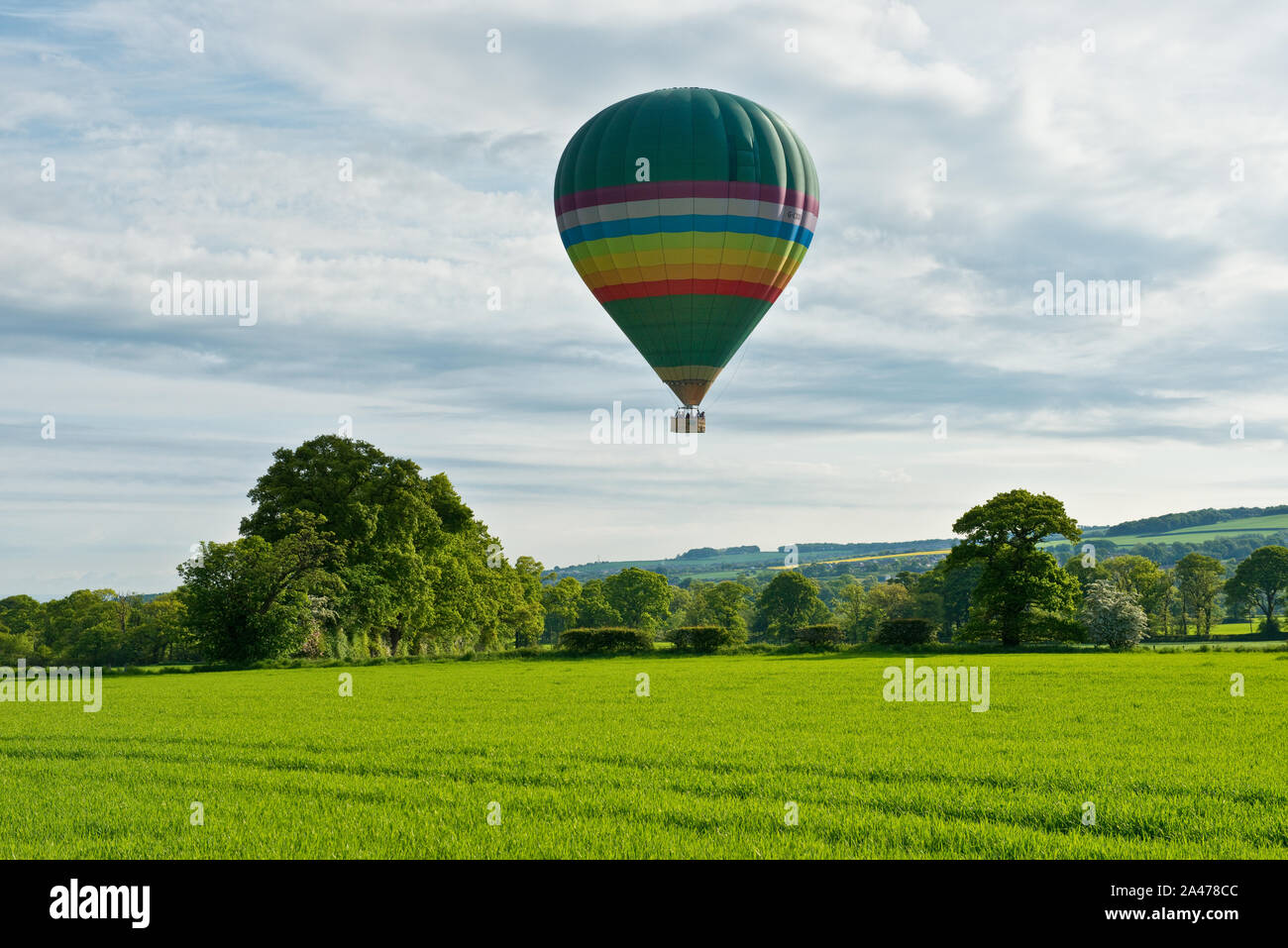 Hot air balloon flying low over farm fields. Midlothian, Scotland Stock Photo