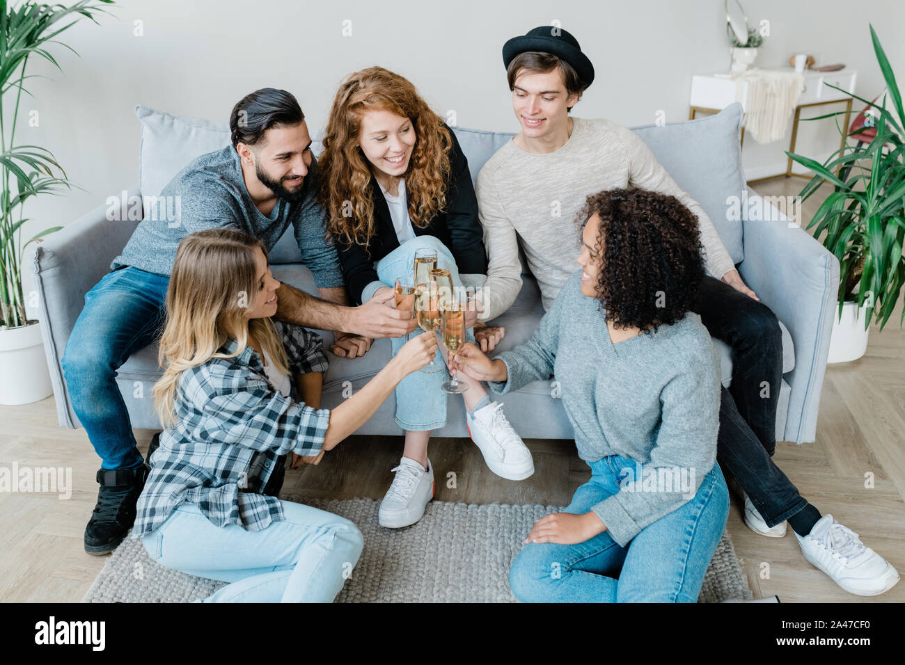 Five young cheerful friends in casualwear clinking with flutes of champagne Stock Photo