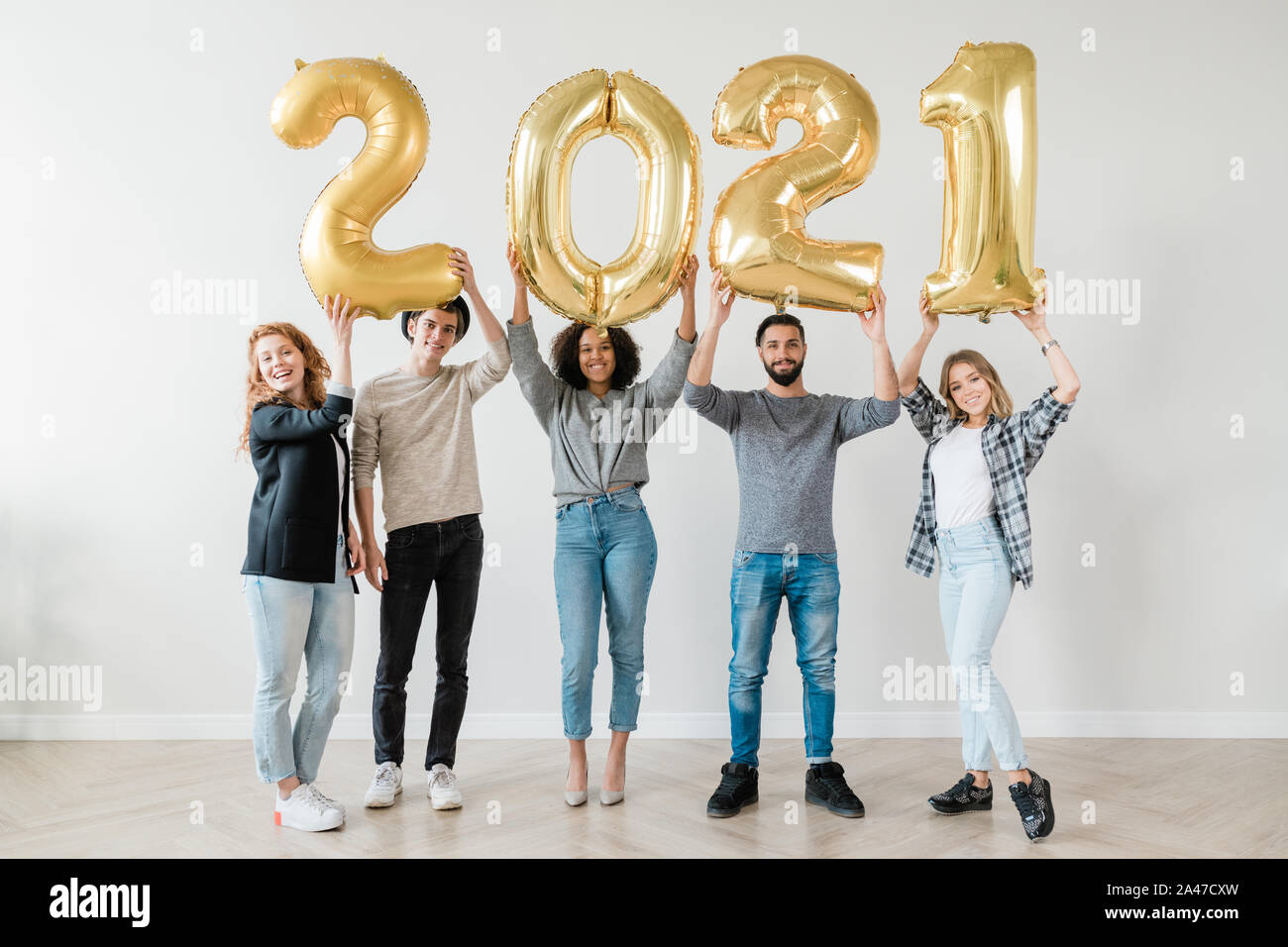 Cheerful guys and girls holding number of new year in raised hands Stock Photo