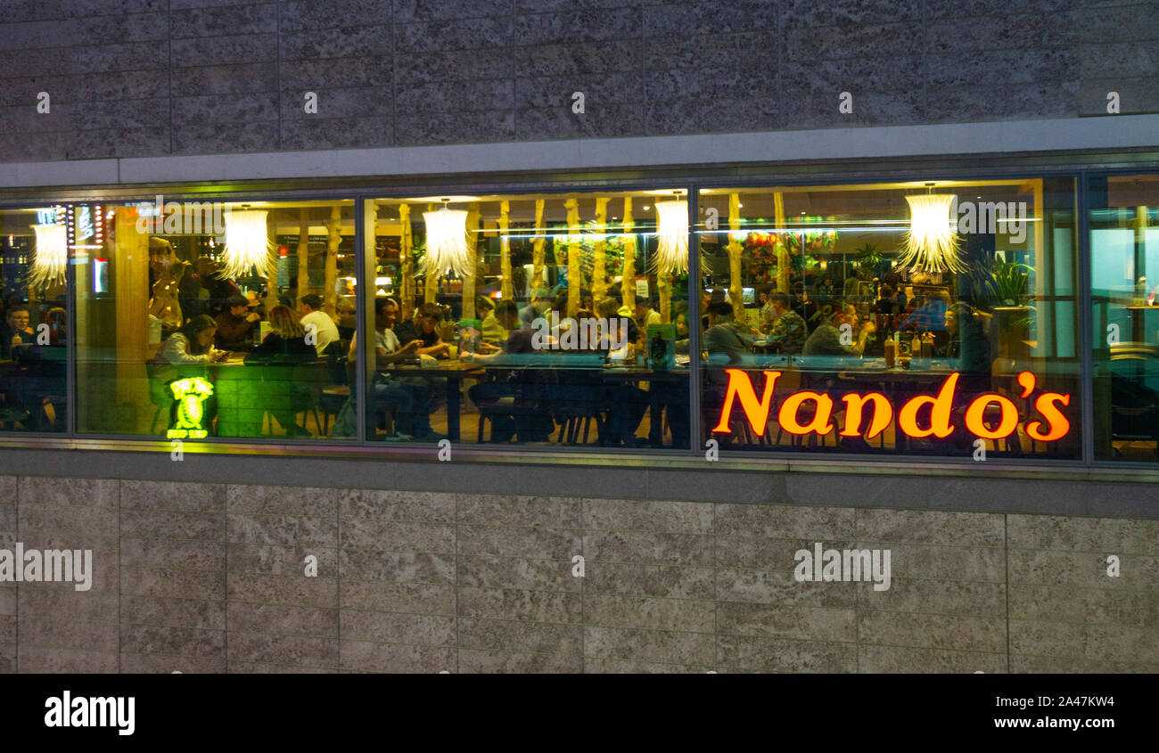 Dining at Nando's South African restaurant at night in Liverpool One shopping centre, England Stock Photo