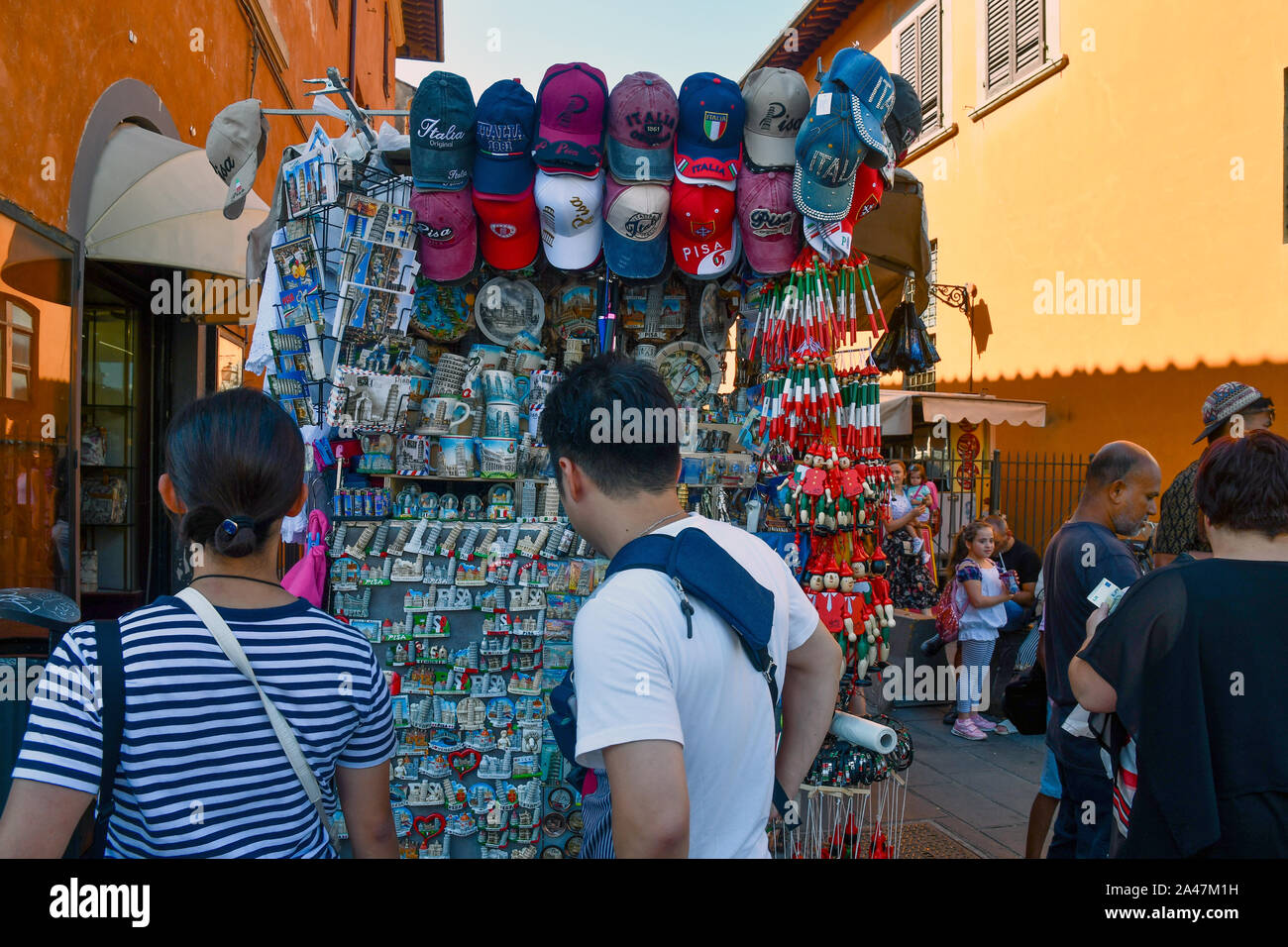 Tourists from behind buying souvenirs at a street stall in the old town of Pisa in summer, Tuscany, Italy Stock Photo