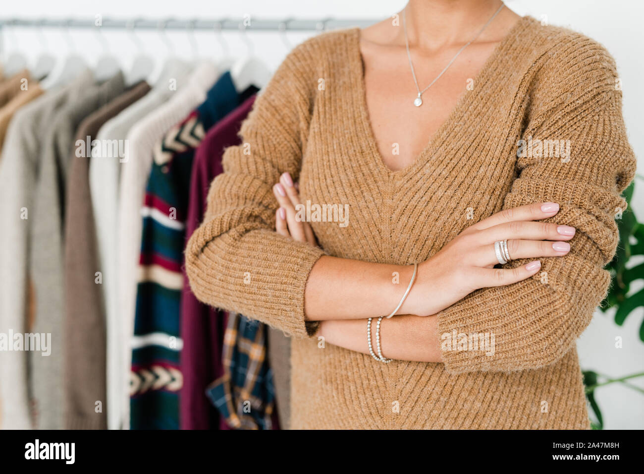 Mid-section of young shop assistant in casual knitted beige pullover Stock Photo
