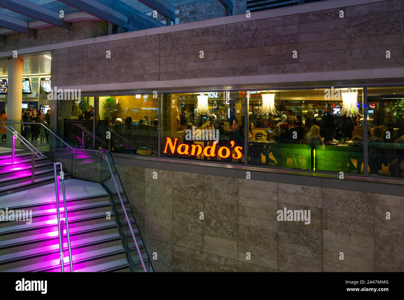 Dining at Nando's South African restaurant at night in Liverpool One shopping centre, England Stock Photo