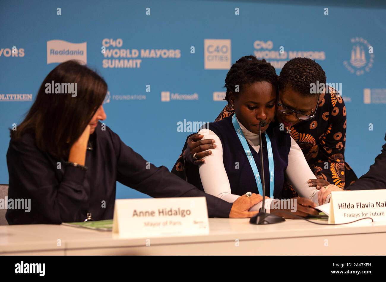 COPENHAGEN, DENMARK – OCTOBER 11, 2019: Hilda Flavia Nakabuye, climate activists within the ‘Fridays for Future’ movement,  Uganda, during the ‘Mayors and Youth Activist’ press conference at the C40 World Mayors Summit. The young activist from Uganda gave a powerful and emotional speech and is here supported by Yvonne Aki-Sawyer (R), Mayor of Freetown, Seattle, and Anne Hidalgo, Mayor of Paris.  During the press conference young activist explained what they expect of the grown-up politicians. More than 90 mayors of some of the world’s largest and most influential cities representing some 700 m Stock Photo