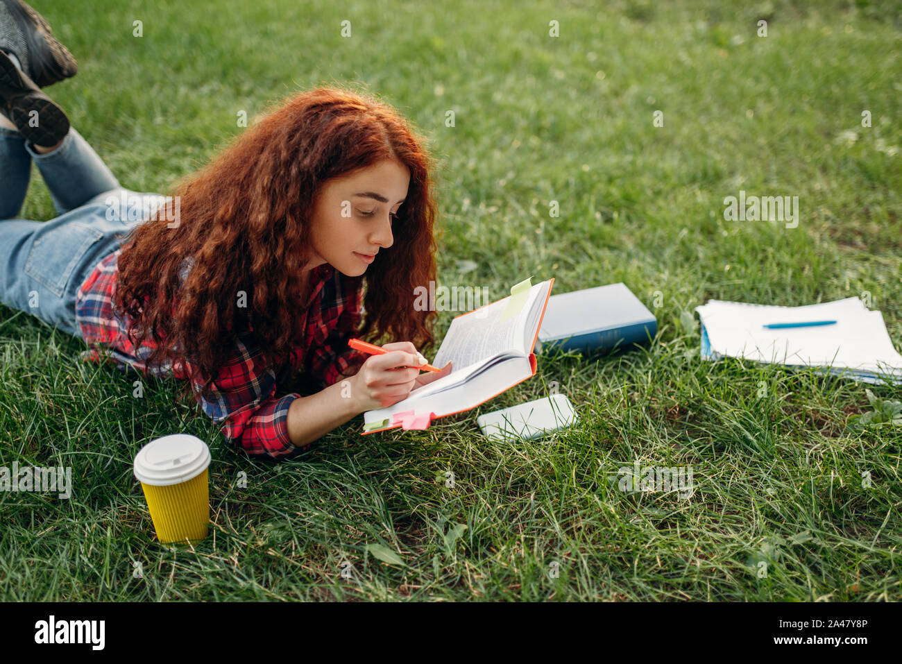 Female student preparing for exams on the grass Stock Photo