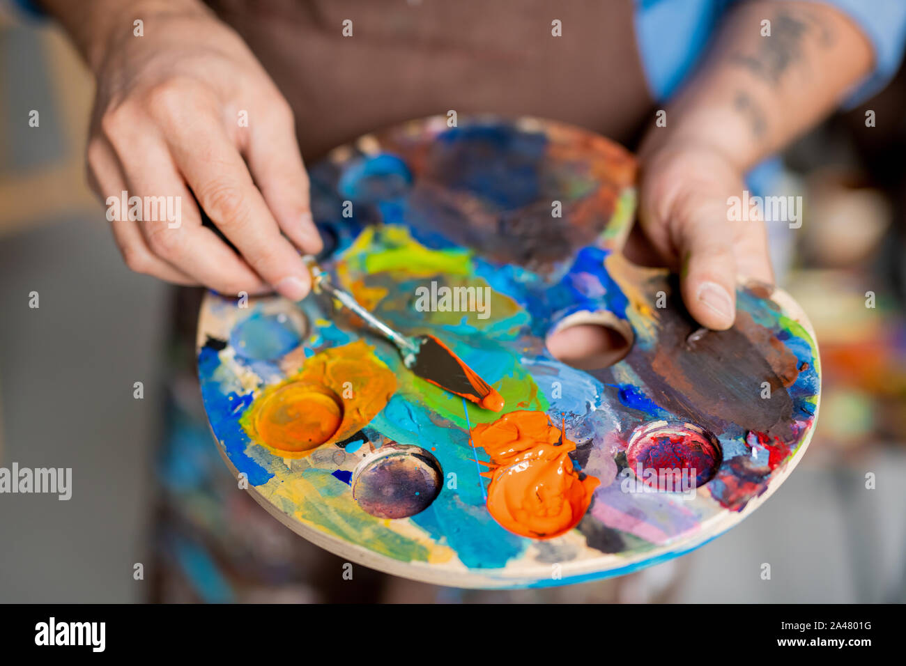 Hand of painter mixing paints on palette with small instrument before painting Stock Photo