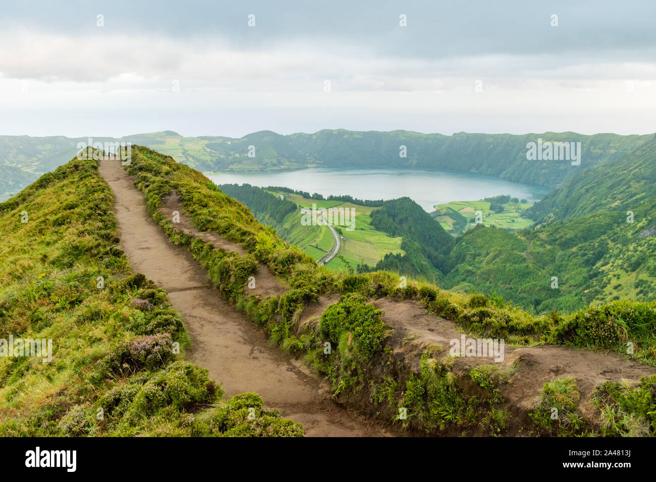 View of a footpath at the Miradouro da Grota do Inferno viewpoint leading towards one of the crater lakes at Sete Cidades on São Miguel in the Azores. Stock Photo