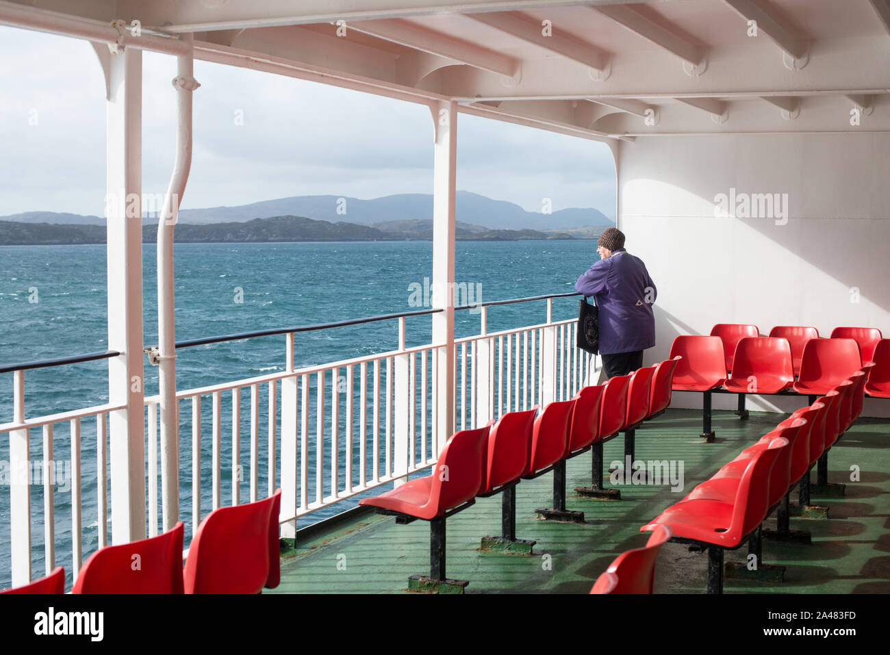 A lone traveller looks out from the deck of a car ferry sailing to the Outer Hebrides, Scotland. UK Stock Photo