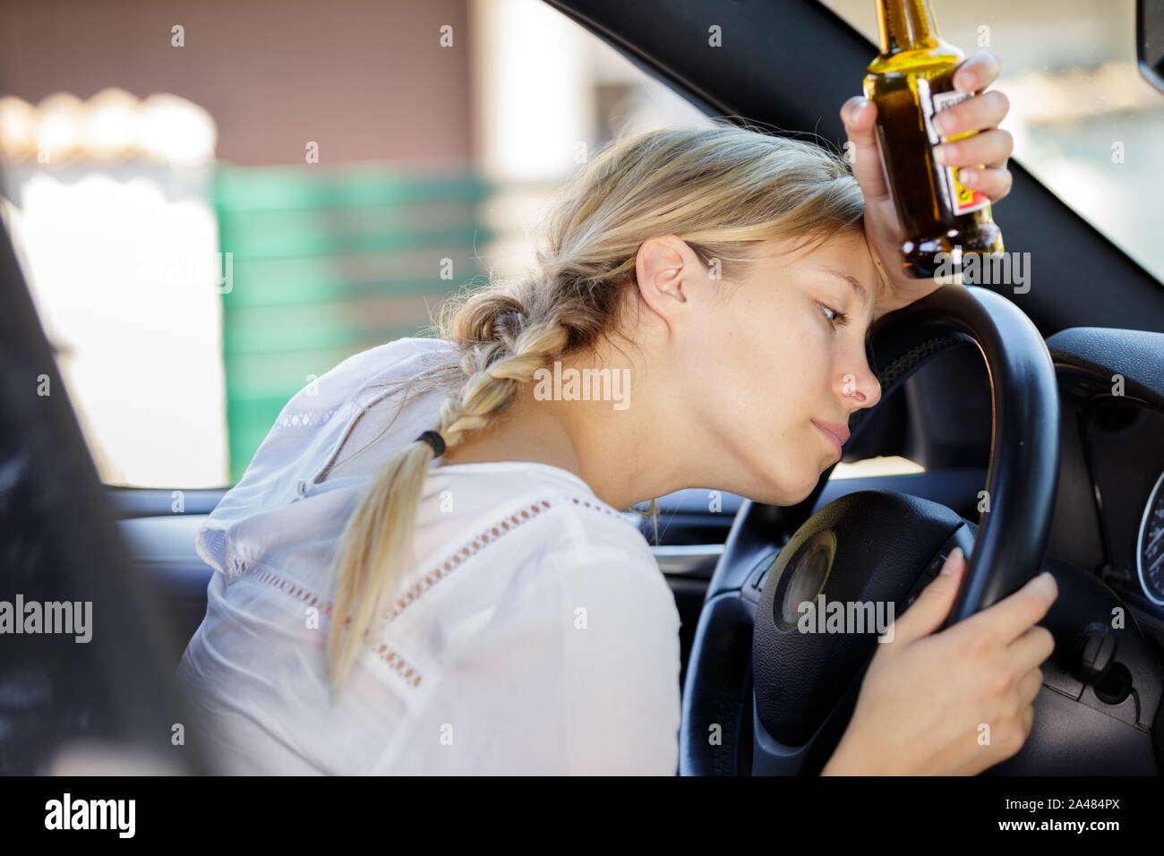 female driver slouched over steering wheel holding beer bottle Stock ...