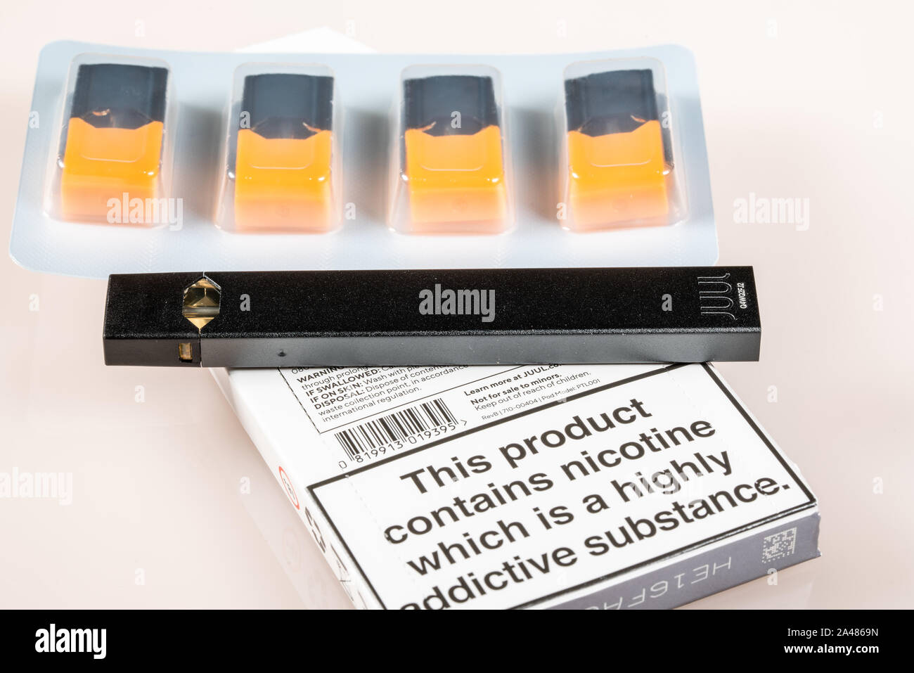 MORGANTOWN, WV - 12 October 2109: Warning sign for Juul e-cigarette or nicotine vapor dispenser box on and flavored JUULpods on light background Stock Photo