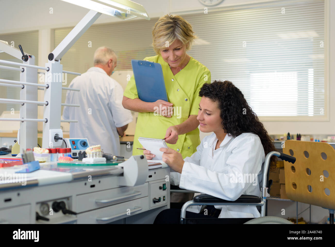 manager assisting wheelchair worker in a lab Stock Photo